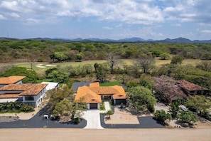 A residential area with multiple houses, a golf course, and a mountainous backdrop.