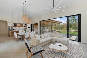 A modern living space with a dining area, a large sofa, and a coffee table.