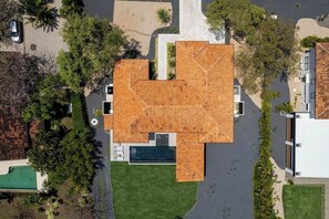 A modern house with a unique geometric roof design, surrounded by a well-maintained lawn and trees.