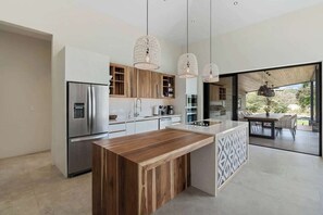 A modern kitchen with a wooden island, stainless steel appliances, and pendant lighting.