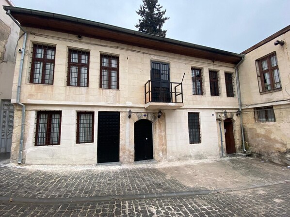 A two-story building with a central entrance, multiple windows, and a small balcony.
