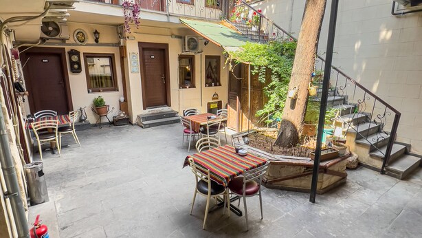 Un patio con una mesa y sillas, un extintor y una escalera que conduce a un nivel superior.