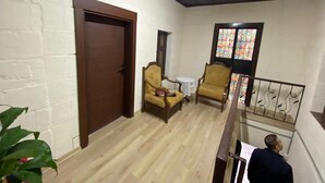 Una habitación con puerta de madera, una mesita, dos sillas y una ventana con vidrieras.
