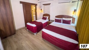 Habitación de hotel con dos camas, suelo y techo de madera, un espejo, un lavabo y una ventana.