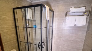 Un baño con ducha separada por mampara de vidrio, inodoro y lavamanos.