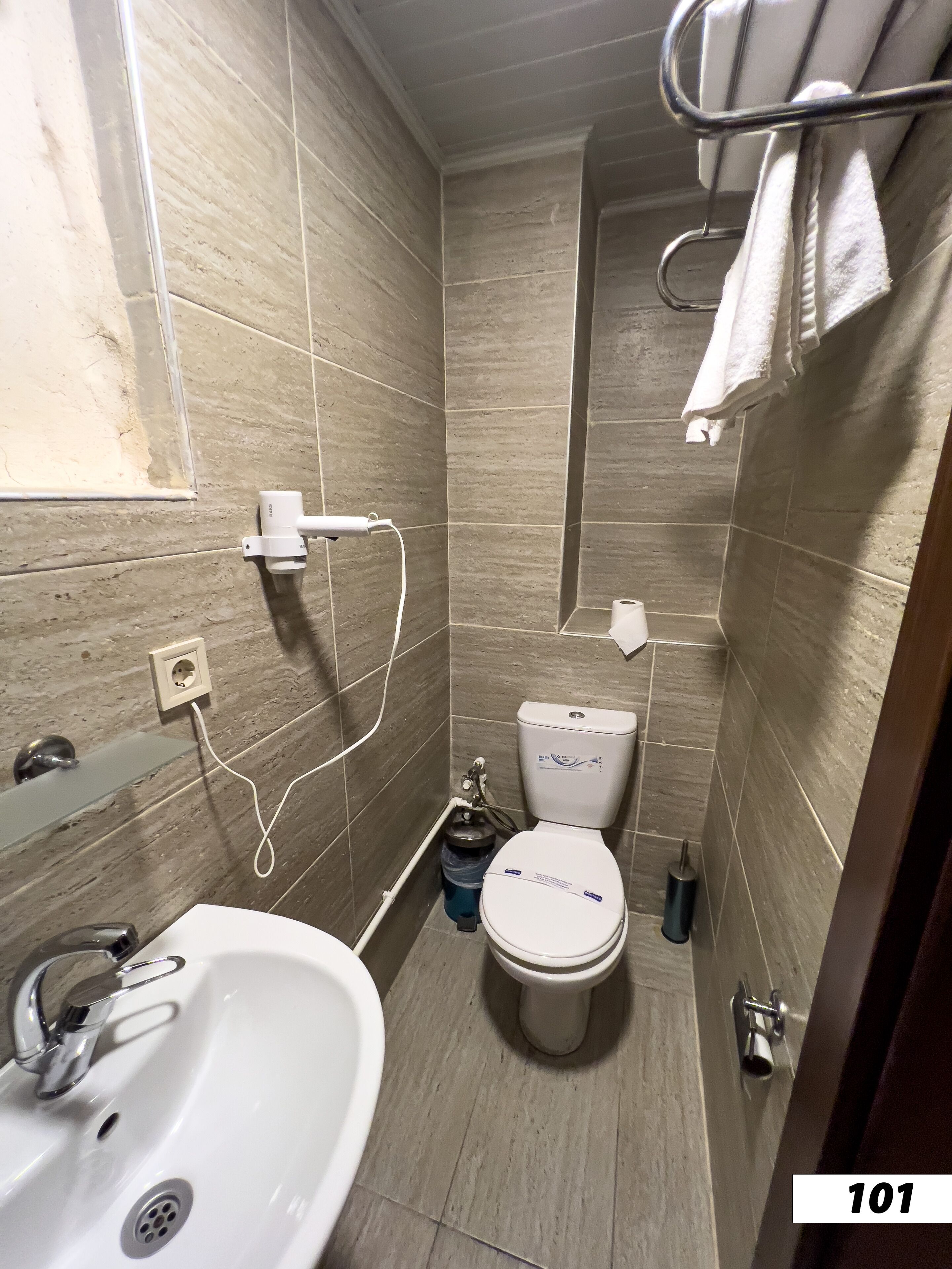 A compact bathroom with a white sink, toilet, and shower.