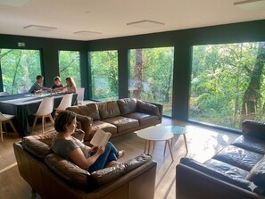 A modern interior with a leather sofa, a dining table, and large windows offering a view of greenery. - Le Triangle D'or - Le Bouleau - Piscine - Gaillac (Gaillac)