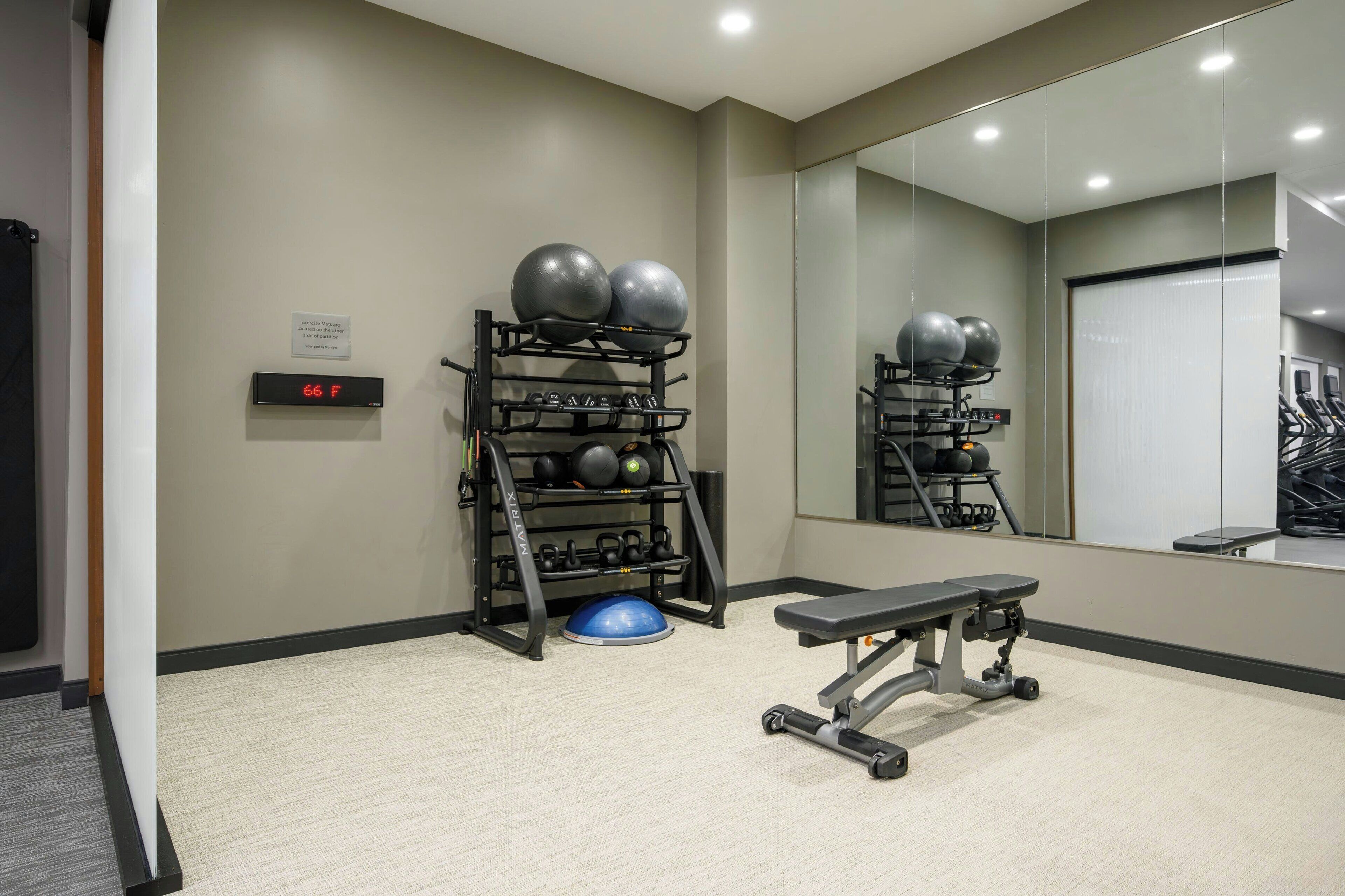 A gym with exercise equipment, a bench, and a digital thermometer.