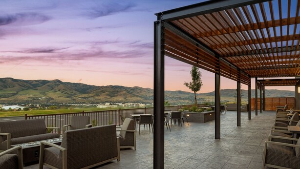 An outdoor patio with wicker furniture and a view of distant hills. - Courtyard BY Marriott Pocatello (Pocatello)