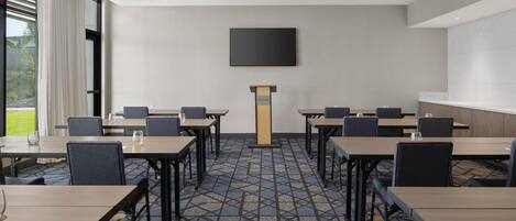 A conference room with a large screen, a podium, and a patterned carpet.