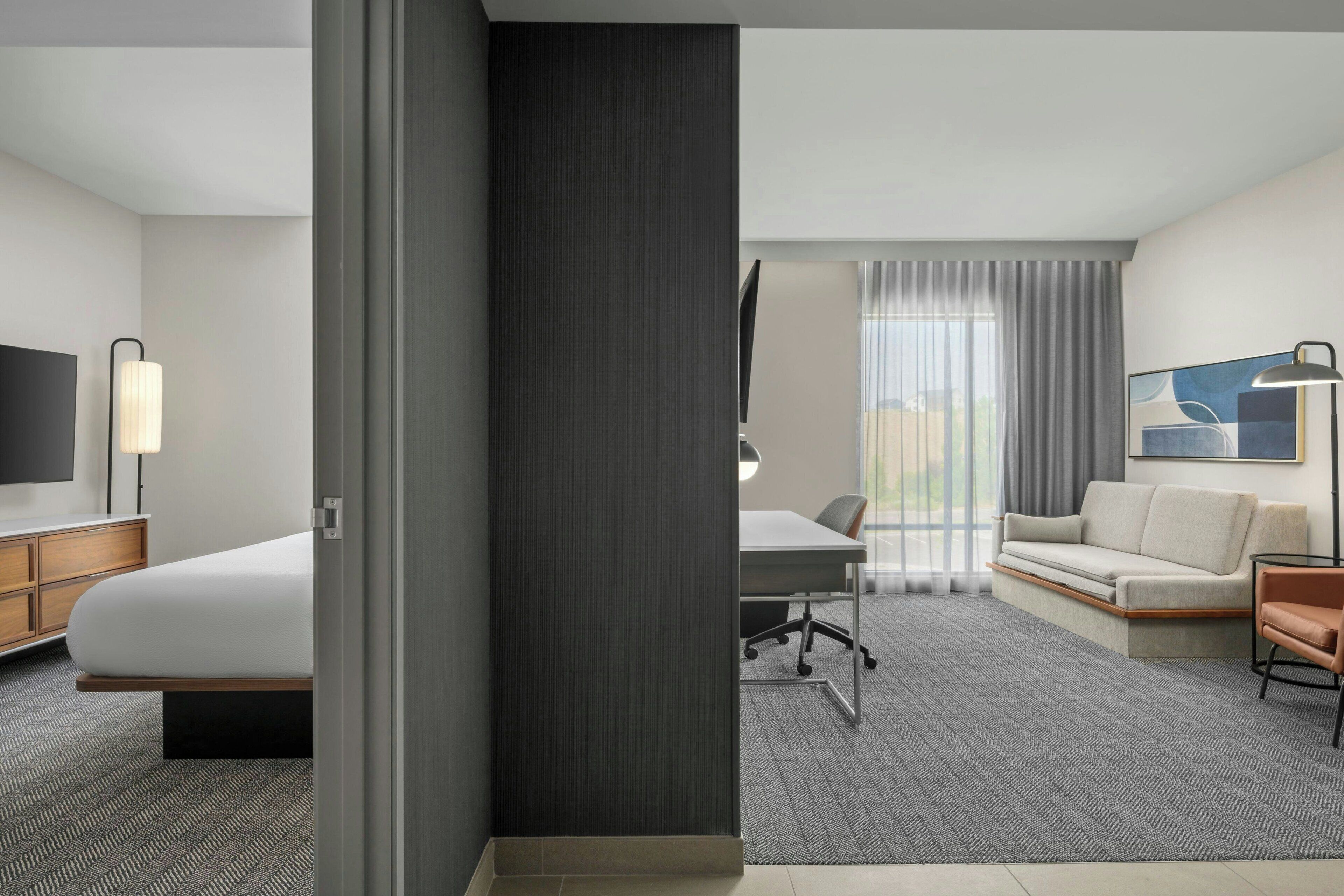 A hotel room with a bed, desk, and sofa.
