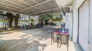 An outdoor covered area with a table and chairs, a metal roof, and parked motorcycles. - Hotel O Ada Guest House (Medan)