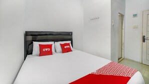 A hotel room with a bed, white walls, a black headboard, and red pillows with the word "OYO" on them. - Hotel O Ada Guest House (Medan)