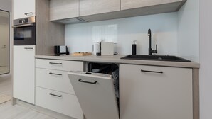 A modern kitchen with a dishwasher, oven, and sink. - Cozy Apartment | Close to Beach and Lake, Parking. (Mielno)