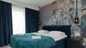 A modern bedroom with a large bed, dark curtains, a wall mural, and a bedside table. - Cozy Apartment | Close to Beach and Lake, Parking. (Mielno)
