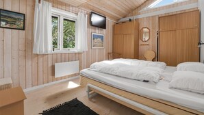 A wooden-paneled bedroom with a bed, a TV, and a window with curtains. - Stunning home in Vestervig with sauna (Vestervig)