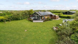 A modern house with a large lawn, a patio, and a wooden deck. - Stunning home in Vestervig with sauna (Vestervig)