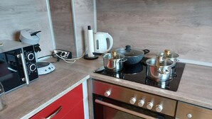 Une cuisine équipée d’une cuisinière, de casseroles, d’une bouilloire et d’une machine à café.