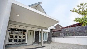 Un edificio moderno con techo plano, entrada cubierta y un patio empedrado.