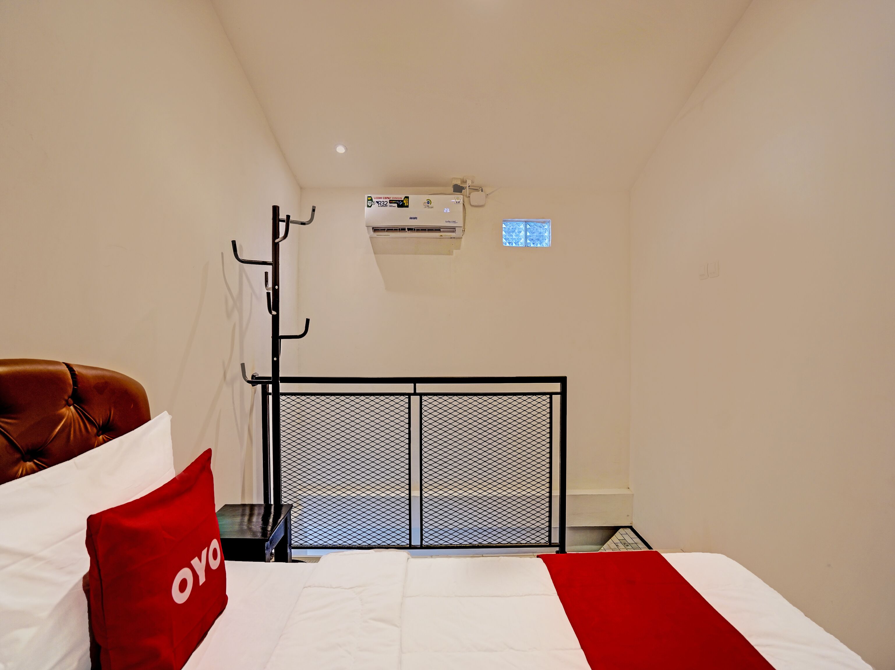 A hotel room with a bed, a red and white bedspread, a brown leather chair, a small table, and a window with a view.