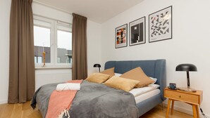A neatly arranged bedroom with a bed, bedside table, and a window with curtains.