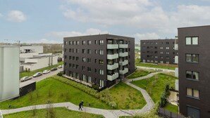 A modern apartment complex with multiple floors, balconies, and a well-maintained green courtyard.
