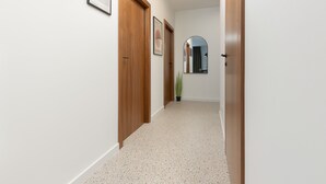 A hallway with wooden doors, framed artwork, and a potted plant.