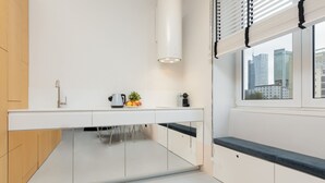 Une cuisine moderne avec des meubles blancs, une cuisinière encastrée et une fenêtre donnant sur la ville.