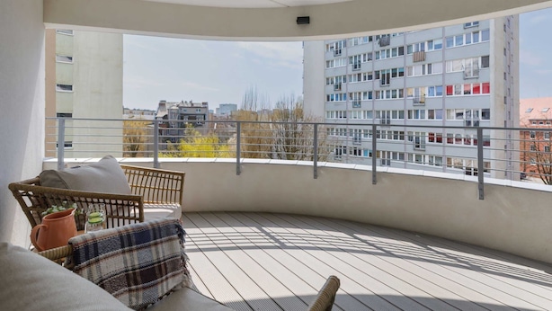 A balcony with a wicker chair, a plaid cushion, and a potted plant. - Comfortable Apartment | Balcony | Parking | Close to Park (Swinoujscie)