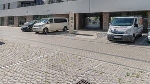 A modern multi-story building with a curved facade, a covered parking area, and a pedestrian bridge. - Comfortable Apartment | Balcony | Parking | Close to Park (Swinoujscie)
