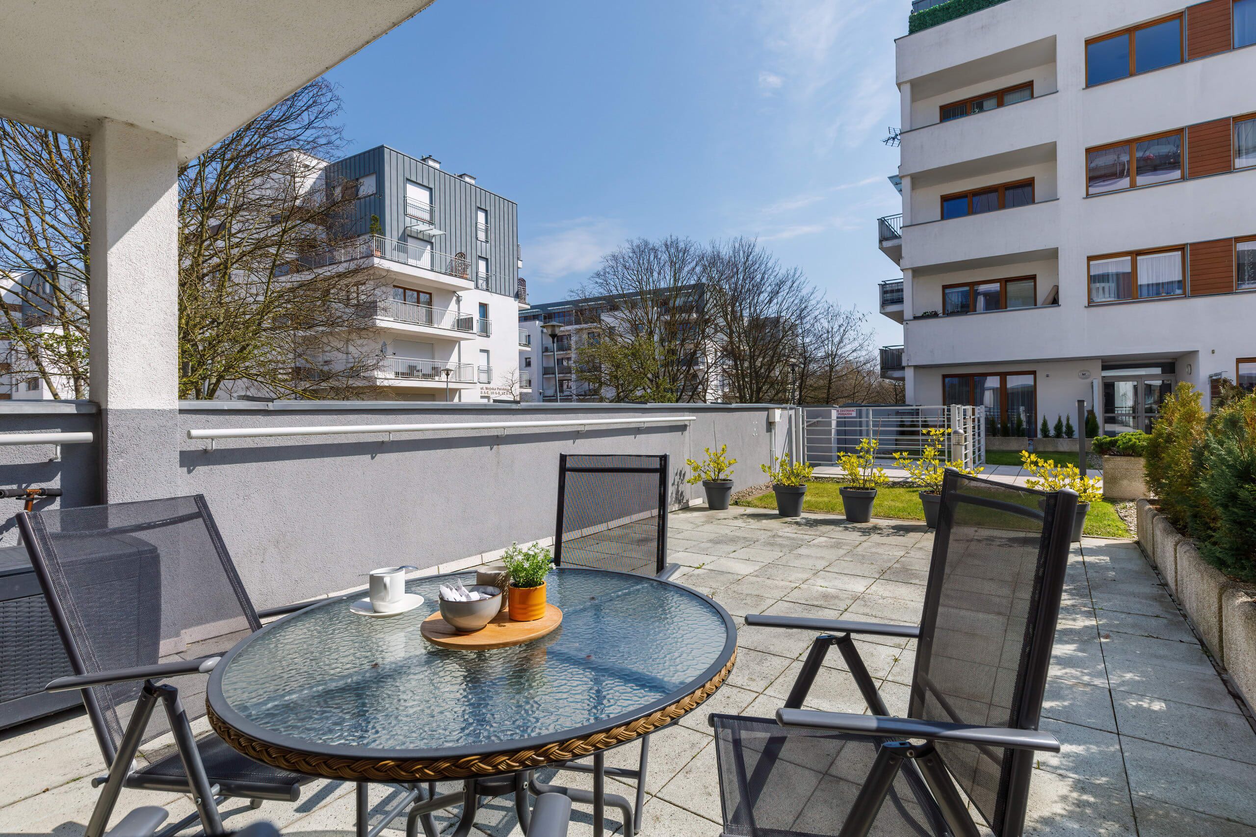 Ein runder Glastisch mit Stühlen auf einem Balkon mit Blick auf ein Wohngebiet und moderne Gebäude.