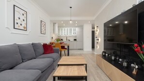 A modern living room with a grey sofa, a wooden coffee table, and a kitchen in the background. - Prestigious Apartment | Jacuzzi and Balcony (Dziwnów)