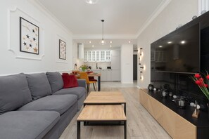 Una sala moderna con un sofá gris, una mesa de centro de madera y una cocina al fondo.