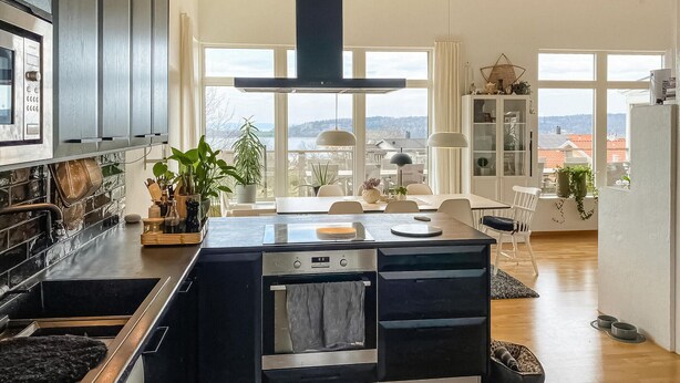 Una cocina moderna con una isla grande, horno empotrado y vistas a la ciudad a través de amplios ventanales.