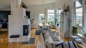 Amplia sala de estar con chimenea, mesa de comedor y ventanas grandes con vista a la ciudad.