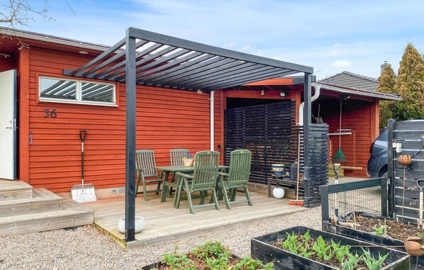 A patio with a pergola, outdoor seating, and a garden area with plants.