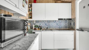 A modern kitchen with white cabinets, a patterned backsplash, and a built-in oven.