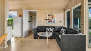 A modern living room with a grey sofa set, a small round table, and a painting on the wall.