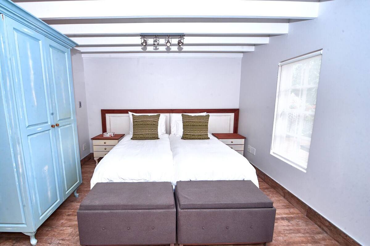 Un dormitorio con una cama grande, dos mesitas de noche, un armario y una ventana.