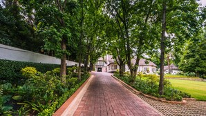 A paved pathway leading to a building surrounded by lush greenery and trees. - Sandton Country Manor (Sandton)