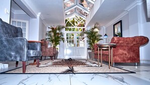 A spacious lobby with a high ceiling, a central rug, and two sofas. - Sandton Country Manor (Sandton)