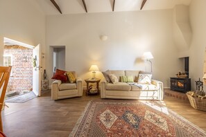 Un accogliente soggiorno con due divani, un tappeto decorato, un camino e un muro in mattoni rustici.