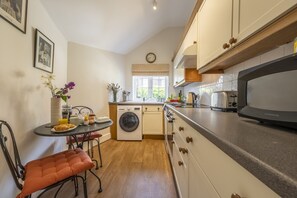 Una cucina funzionale con lavatrice, un tavolo da pranzo con sedie e forno a microonde.