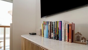 A bookshelf with various books and a small house model on a white surface. - Skylark (Reydon)