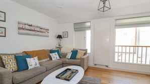 A living room with a sectional sofa, a coffee table, and a painting on the wall. - Skylark (Reydon)