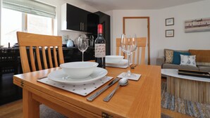 A dining table set with plates, cutlery, and wine glasses, with a bottle of wine on the table. - Skylark (Reydon)