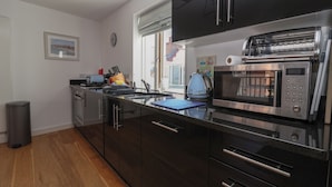 A modern kitchen with stainless steel appliances, wooden cabinets, and a window with a view of the outside. - Skylark (Reydon)