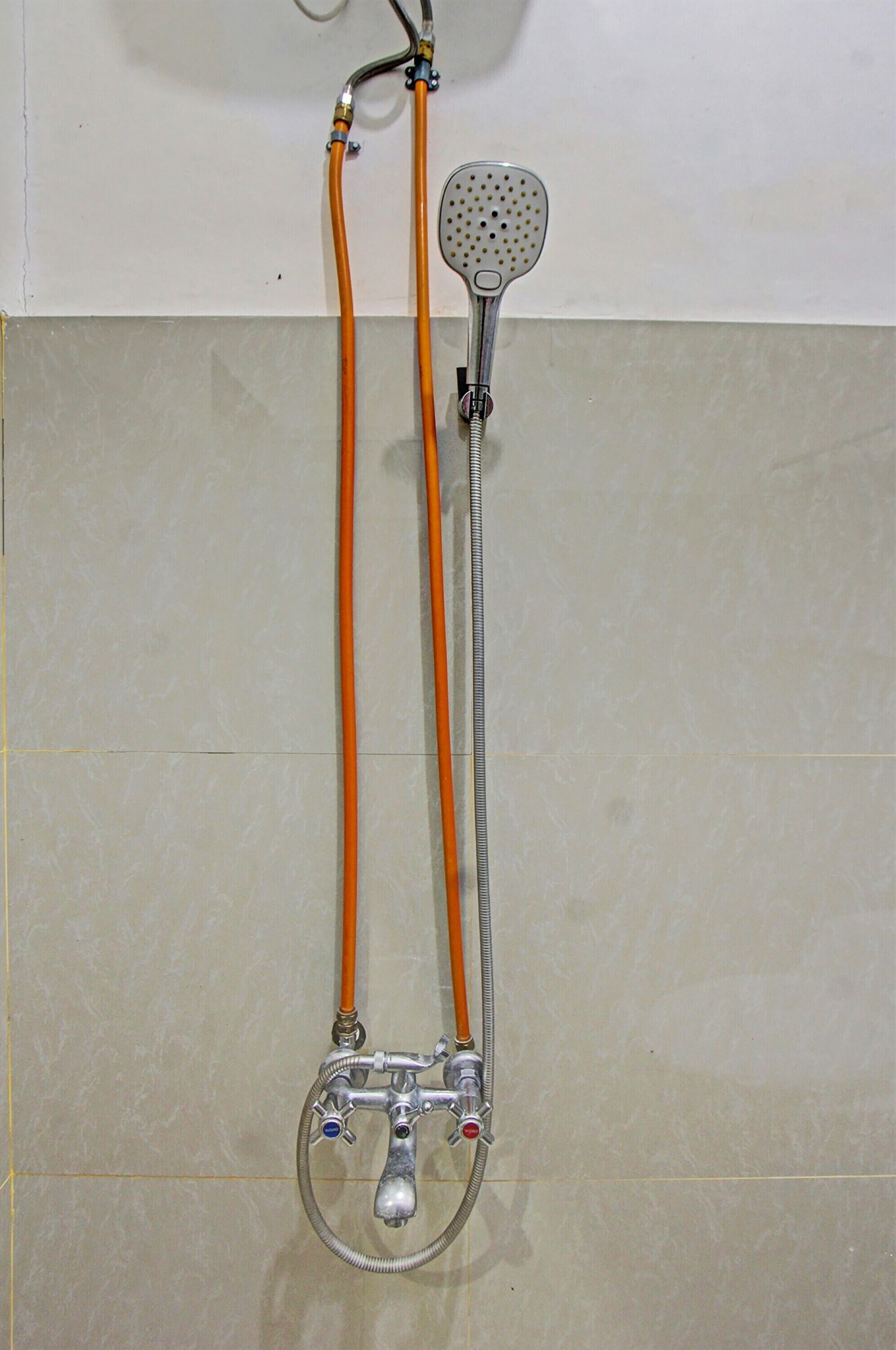 A shower with a handheld showerhead and two hoses.