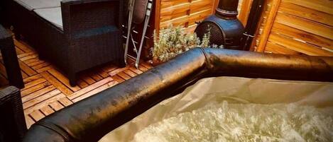 A hot tub with visible water jets, surrounded by wicker furniture and a wooden deck.