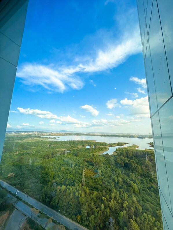 A high-rise building with a view of a river and forested area.